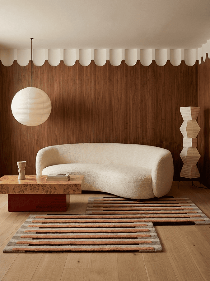 Still Movement hand tufted rug styled in a minimalist contemporary living room, showcasing its rhythmic linear pattern and warm, earthy tones.