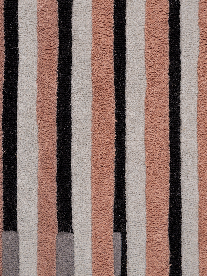 Close-up of Still Movement rug highlighting the precise vertical stripes, textured wool pile, and the contrast between terracotta and charcoal tones.