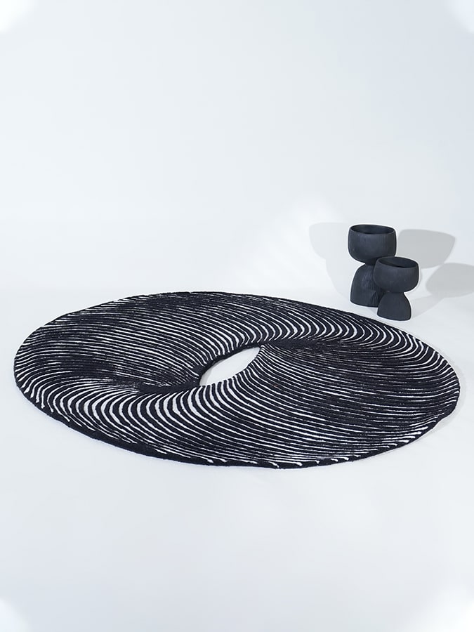 Cosmic Ring Rug featuring a captivating black and white pattern with a central circular void, hand-tufted from New Zealand wool.