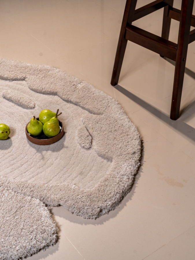 Moon Pond hand-tufted circular rug in ivory and grey with layered high-low textures.