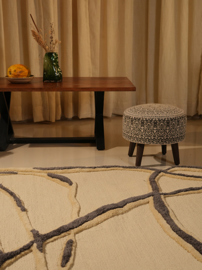 Hand-tufted rug with sculptural pile and abstract black line design.