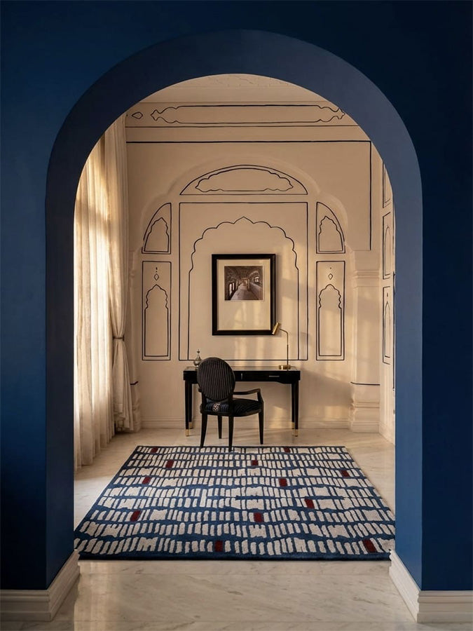 Tactile Code hand-tufted rug with rhythmic neutral line patterns on a deep indigo base and subtle red accents.