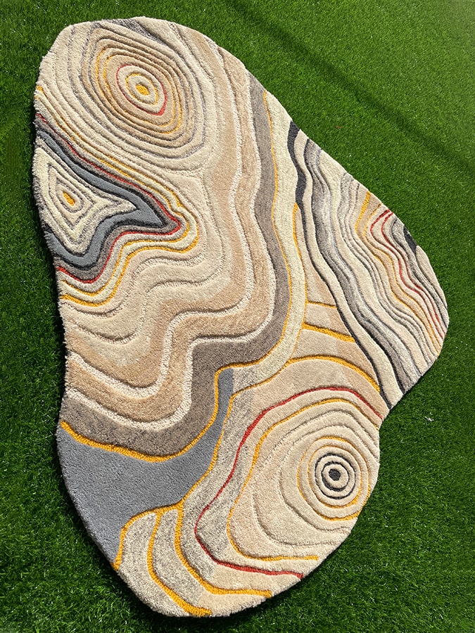 Top view of the Uncanny Valley Rug on the floor, showcasing its versatility and the unique pattern inspired by nature's ripples.