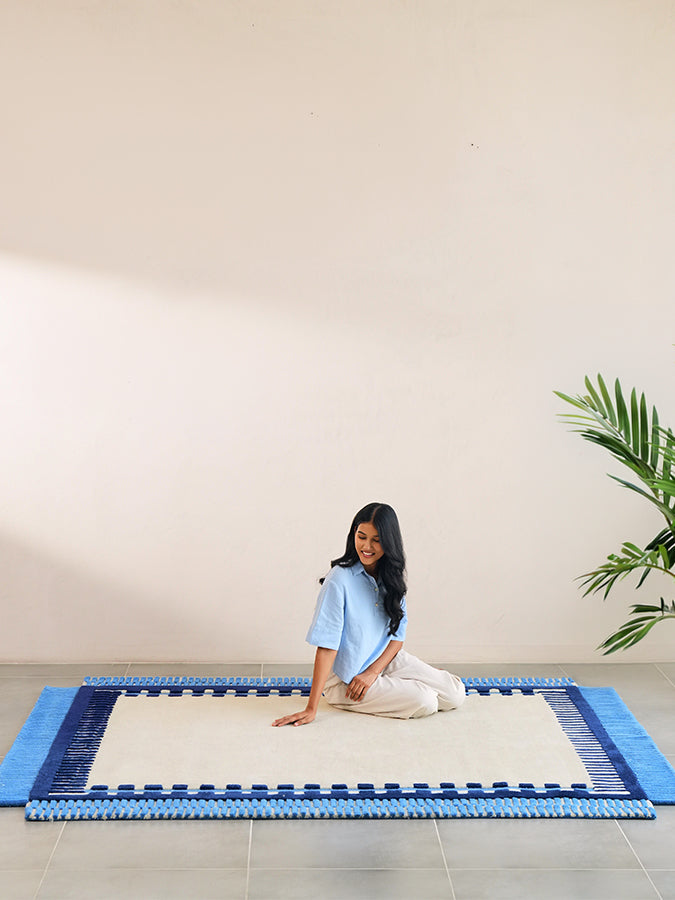 Full view of Nested blue and ivory hand tufted rug with a navy frame and stepped striped edges